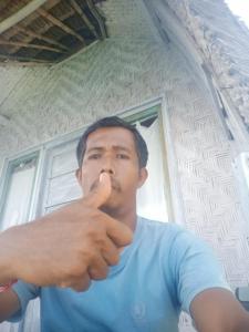 a man brushing his teeth in front of a window at Eco Tourist Dream Stay Tree House in Nusa Penida