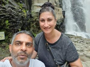 a man and a woman standing in front of a waterfall at Eco Tourist Dream Stay Tree House in Nusa Penida