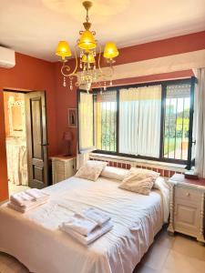 a bedroom with a large white bed with a chandelier at Villa Rural junto a la playa - SUN & RELAX in Marbella