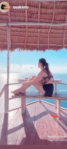 a woman sitting on a bench by the water at Eco Tourist Dream Stay Tree House in Nusa Penida