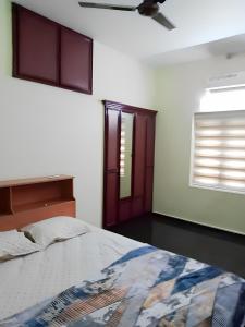 1 dormitorio con 1 cama y ventilador de techo en Cloudnine Home Thrissur en Trichūr
