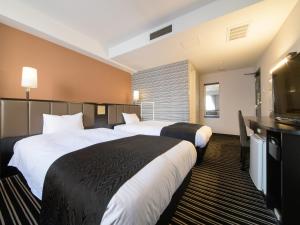 um quarto de hotel com duas camas e uma televisão de ecrã plano em APA Hotel TKP Sapporo Ekimae em Sapporo