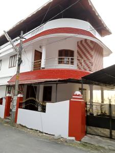 um edifício branco e vermelho com um telhado vermelho em Cloudnine Home Thrissur em Thrissur