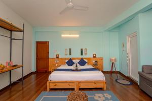 a bedroom with a large bed with blue walls at Chokling ArtHouse - The Treasure of Himalayas in Bīr