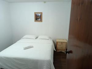 Un dormitorio con una cama blanca y una foto en la pared en Graces Hospedaje, en Baños