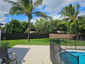 a backyard with a pool and a chair and palm trees at Sunny Goldie in Lauderdale Lakes