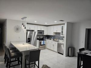 a kitchen with white cabinets and a table with chairs at Sunny Goldie in Lauderdale Lakes