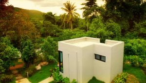 a white house in the middle of a garden at Rivercreek Estate in Kaeng Krachan