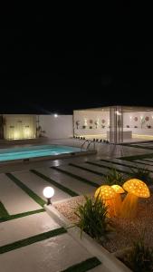 a swimming pool at night with umbrellas next to it at The sunset farm in á¸¨aÅŸat al BidÄ«yah