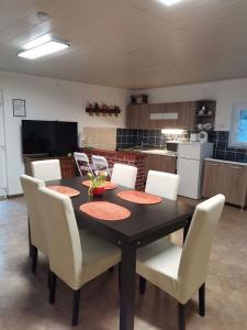 a dining room table with white chairs and a kitchen at Sasvár Vendégház in Parádsasvár