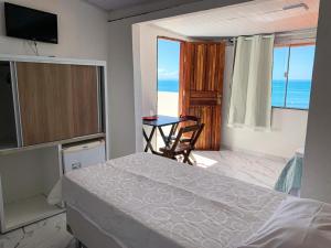 a bedroom with a bed and a table with a view of the ocean at Pousada Ilha do Sol in Morro de São Paulo