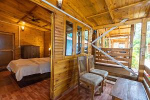 a bedroom in a log cabin with a bed and a chair at Hitide Beach Resort in Palolem