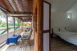 1 dormitorio con cama y balcón con mesa y sillas. en Hitide Beach Resort en Palolem