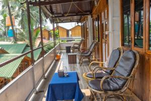 eine Veranda mit Stühlen und einem Tisch mit einem blauen Tisch in der Unterkunft Hitide Beach Resort in Palolem