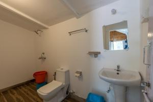 a white bathroom with a toilet and a sink at Hitide Beach Resort in Palolem