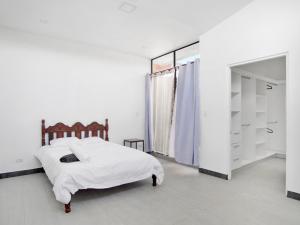 a white bedroom with a bed and a mirror at Apartamento Bellavista en San Jose in San José