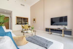 sala de estar con sofá blanco y TV de pantalla plana en Frank Porter - Ansam Building 1 - Yas Island, en Abu Dabi