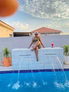 une femme en bikini assise à côté d'une piscine dans l'établissement Minnestay Guest House, à Palatswe