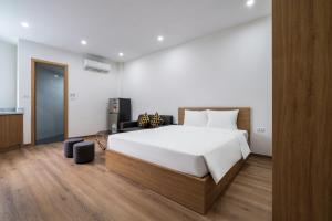 um quarto com uma grande cama branca e uma secretária em Casa Feliz Serviced Apartment em Hanói