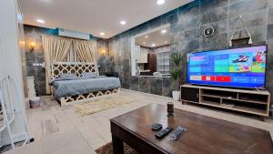 a living room with a large television and a bedroom at ستوديو دور ارضي كامل بمطبخ وحوش وكراج خاص. in Al Hofuf