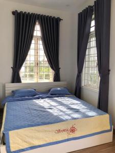 a bed in a bedroom with two windows at Nhat Long Homestay in Hue