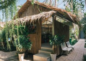 un pequeño edificio de bambú con una escalera y una silla en Homestay Bến Tre, en Ben Tre
