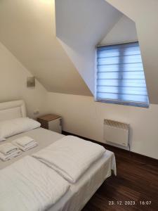 a bedroom with a white bed and a window at Castello apartman Kopaonik in Kopaonik