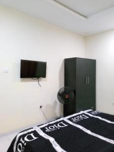 a bedroom with a bed and a flat screen tv at F&B Service Apartment in Abeokuta