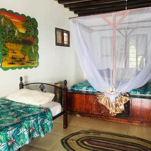 Schlafzimmer mit einem Bett und einem Fenster mit Vorhängen in der Unterkunft Vanilla House in Jambiani
