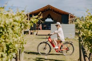 a woman riding a bike in front of a house at Villas & Vines Glamping in Hastings