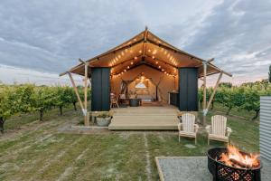 a gazebo with a bed and chairs and a fire at Villas & Vines Glamping in Hastings
