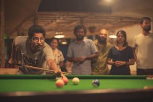 a group of people standing behind a pool table at North & East Arambol I Goa in Arambol