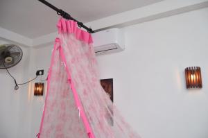une chambre avec un rideau rose suspendu au plafond dans l'établissement Kosi Giggles Resort, à Weligama