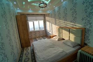 a bedroom with a bed in a room with a window at Family 3-room apartment in Dushanbe