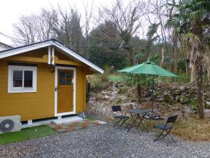 una piccola casa gialla con tavolo e ombrellone di こや・かやき a Yufu