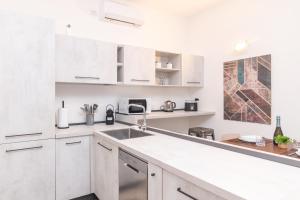 Una cocina blanca con gabinetes blancos y un fregadero. en Secret Garden House - Happy Rentals, en Marina di Portisco