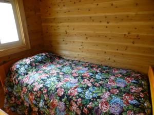 a bed in a wooden room with a floral bedspread at こや・かやき in Yufu