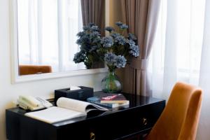 a black dresser with a vase of flowers and a mirror at Le Haute Hotel Hai Phong in Hai Phong