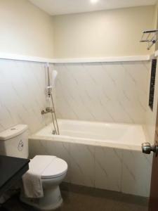 a bathroom with a white tub and a toilet at Sunny Day Residences Cainta in Cainta