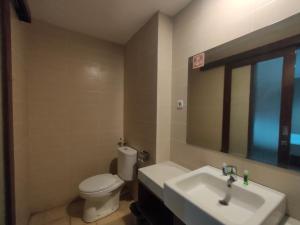 uma casa de banho com um lavatório, um WC e um espelho. em Votel Viure Hotel Jogjakarta em Yogyakarta