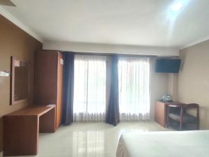 a hotel room with two windows and a bed at Votel Viure Hotel Jogjakarta in Yogyakarta