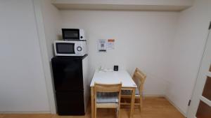a kitchen with a table and a microwave on top of a refrigerator at 札幌市中心部大通公園まで徒歩八分観光移動に便利なロケーションe1007#17 in Sapporo