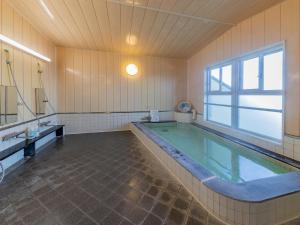 uma grande piscina numa casa de banho com uma janela em Fureaihouse Shiodu no Sato em Sado