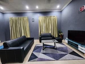 sala de estar con sofá y TV en MumNKidzzz Homestay at Kerteh, en Kampong Pengkalan Pangan