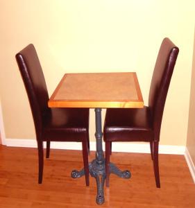 a wooden table with two black chairs around it at Hotel Alila in Saint-Sauveur-des-Monts