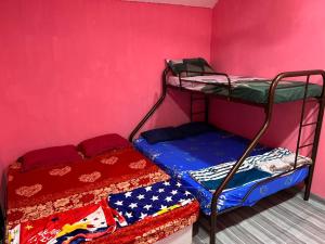 a bedroom with two bunk beds and a pink wall at 吉胆岛海甜民宿 2 Swee Sea Homestay Pulau Ketam 2 in Bagan Teochew +3 photos