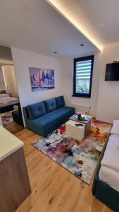 ein Wohnzimmer mit einem blauen Sofa und einem Teppich in der Unterkunft Apartman 506 Aparthotel Zlatni Javor in Jahorina