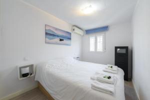 Un dormitorio con una cama blanca con toallas. en Casa familiar Sabadell de 3 dormitorios junto metro Fuencarral, en Madrid
