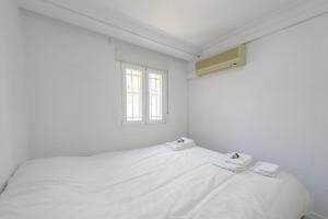 Cama blanca en habitación con ventana en Casa familiar Sabadell de 3 dormitorios junto metro Fuencarral, en Madrid