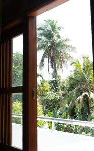 an open window with palm trees in the background at Nalaka Relaxing Home in Weligama